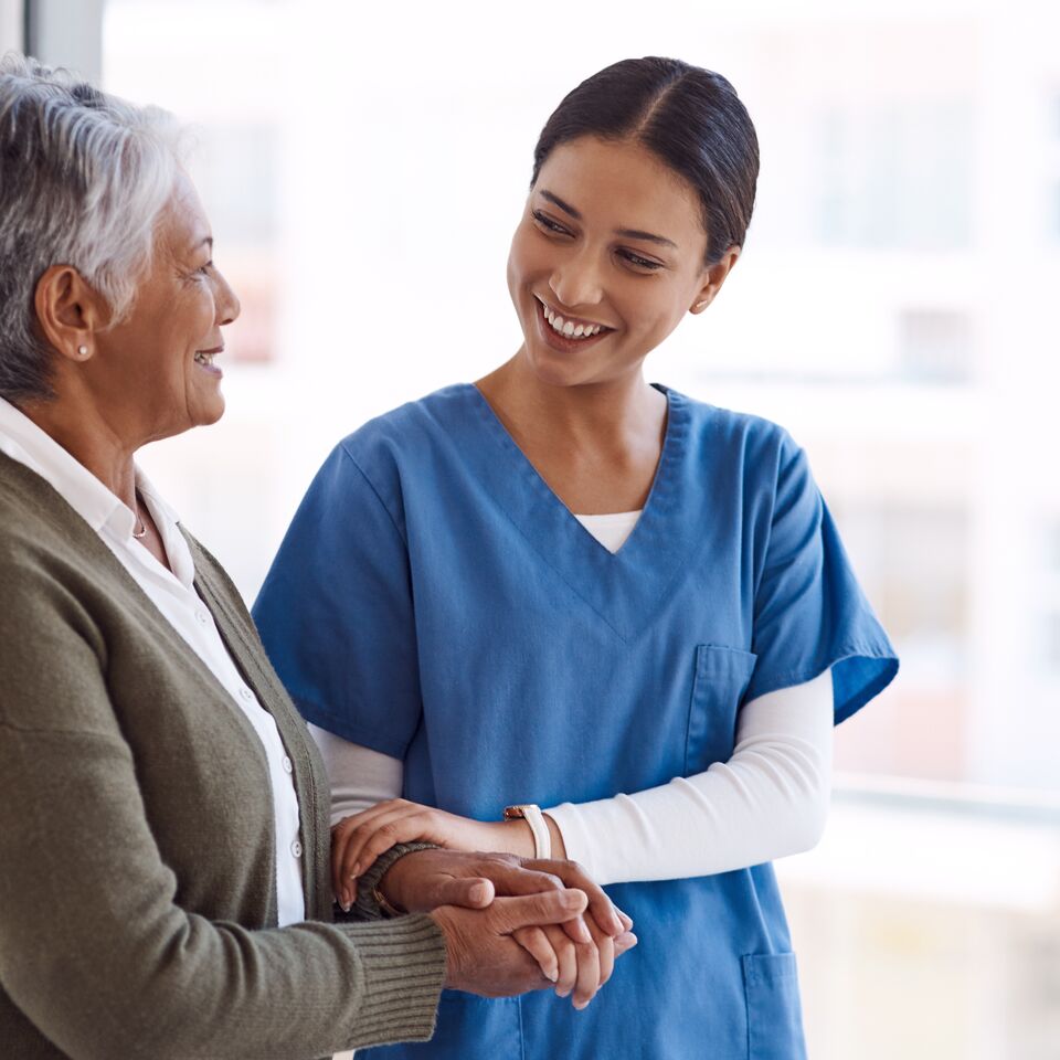 COLOUR-IMAGE_female-nurse-smiling-and-holding-elderly-patient_apr26
