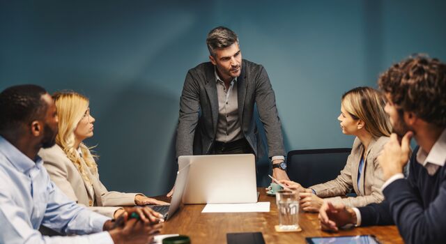 COLOUR-IMAGE_man-standing-in-meeting-discussing-with-his-team_jul26