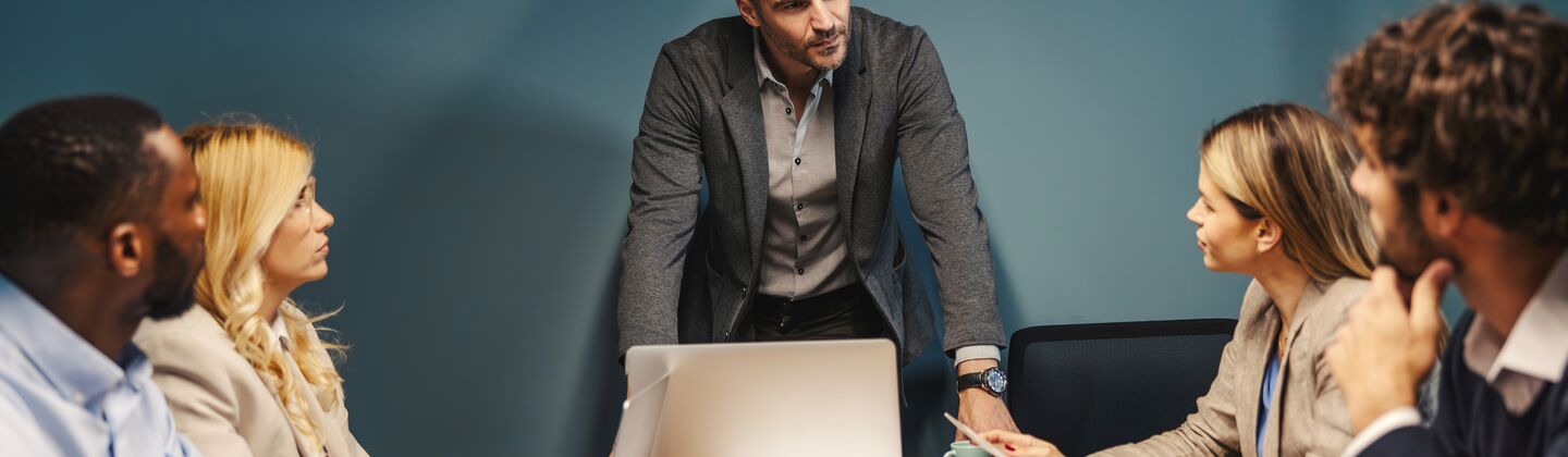 COLOUR-IMAGE_man-standing-in-meeting-discussing-with-his-team_jul26
