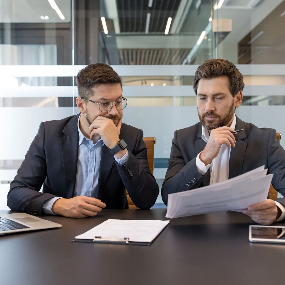 COLOUR-IMAGE_two-men-looking-over-documents-together-at-desk_jul26