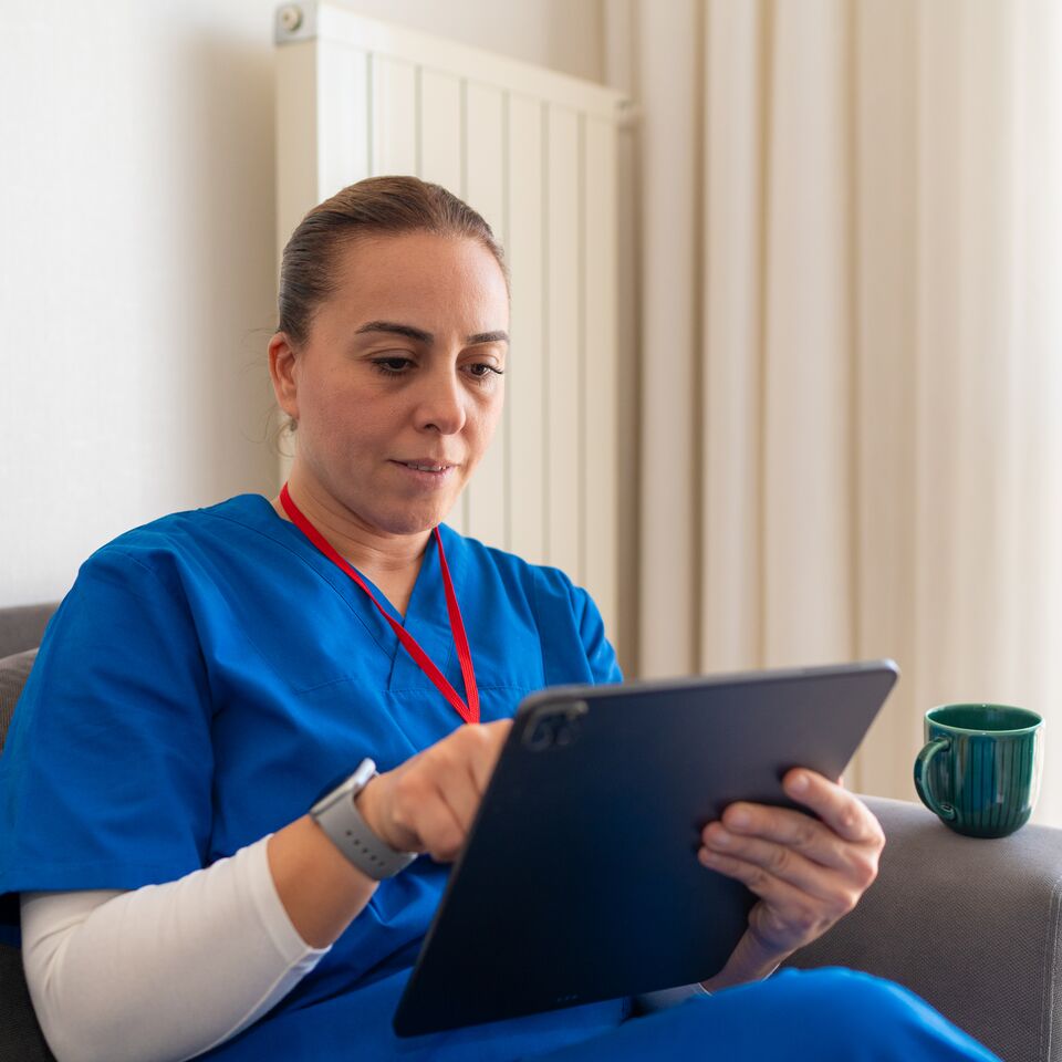 COLOUR-IMAGE_female-nurse-with-red-lanyard-using-tablet-screen_apr26