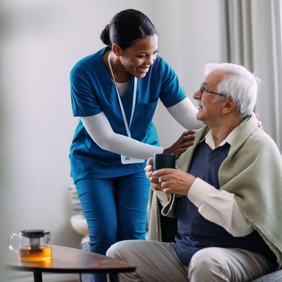 COLOUR-IMAGE_black-female-nurse-smiling-and-caring-for-elderly-patient_apr26
