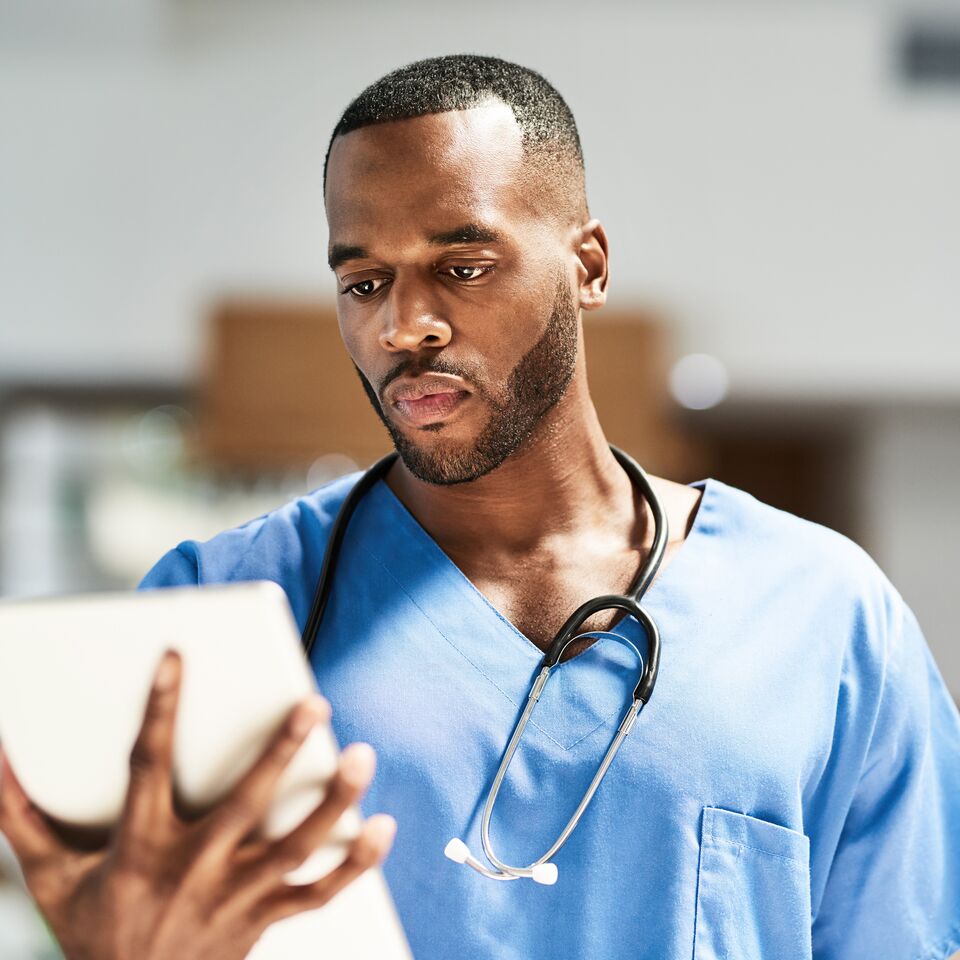 COLOUR-IMAGE_black-male-nurse-checking-tablet-intently_apr26