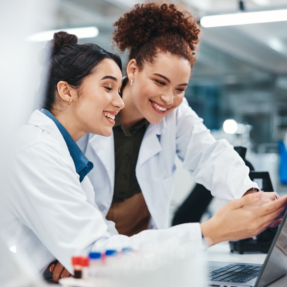COLOUR-IMAGE_life-science-female-lab-technician-smiling-at-laptop_jun26