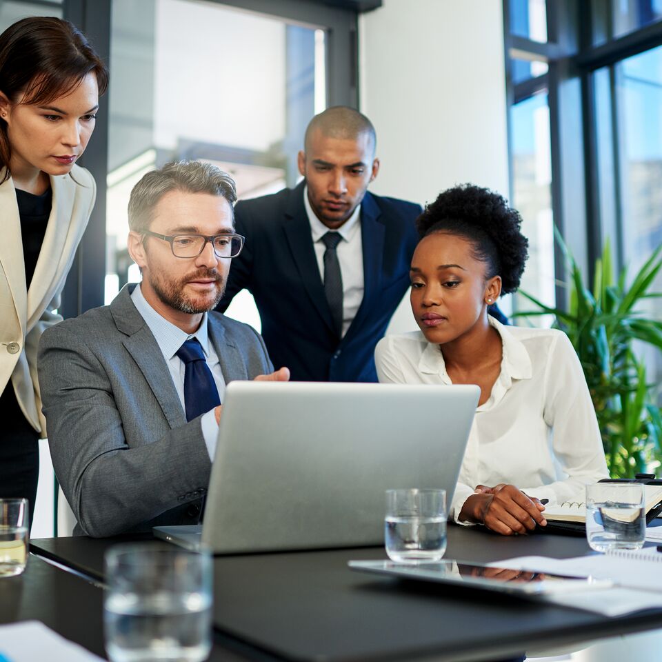 COLOUR-IMAGE_four-professionals-discussing-over-one-laptop-screen_jul26