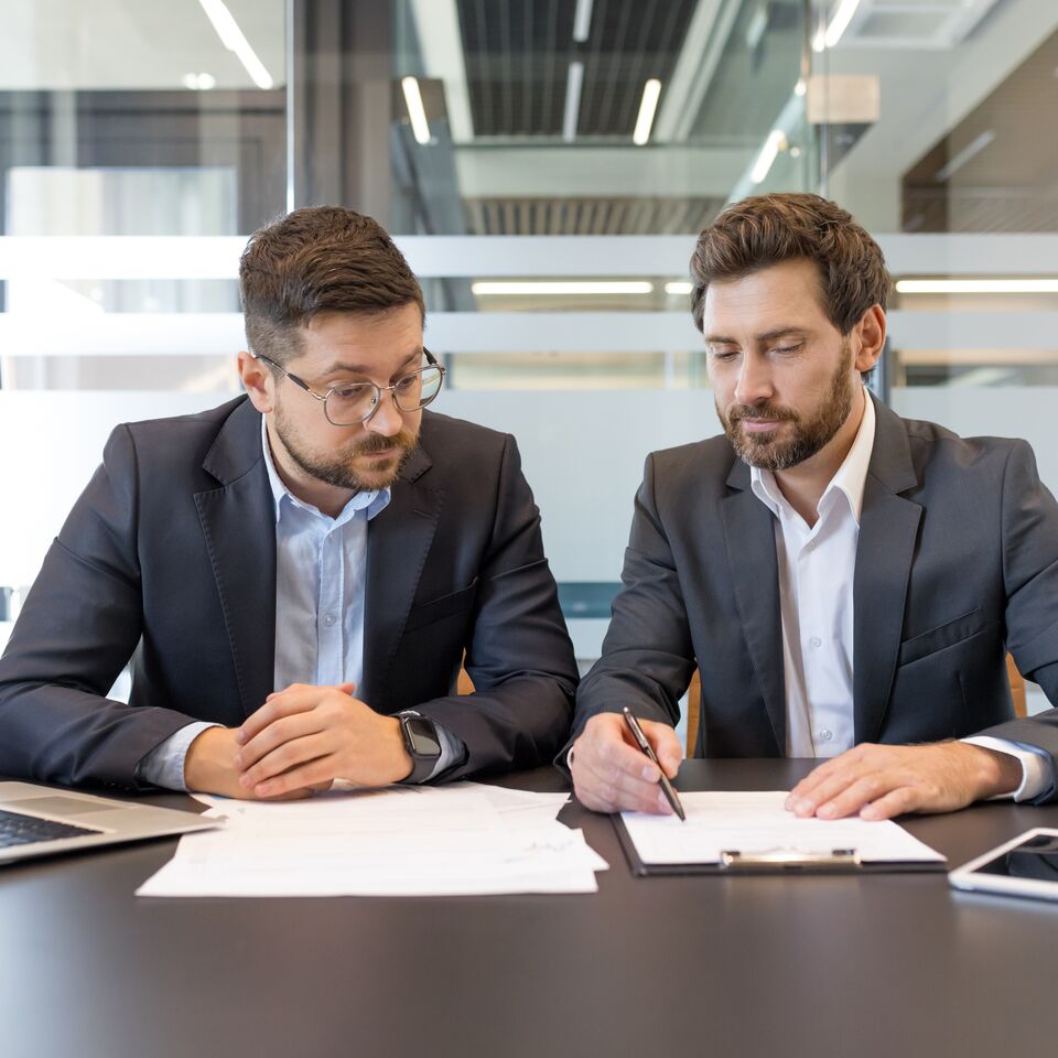 COLOUR-IMAGE_man-pointing-with-pen-to-a-document-showing-his-colleague_jul26
