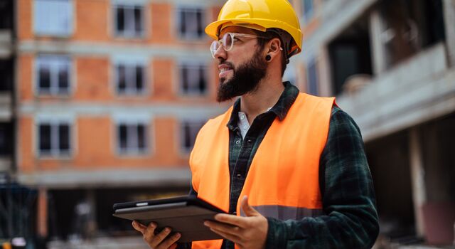COLOUR-IMAGE_construction-worker-standing-tablet_july26
