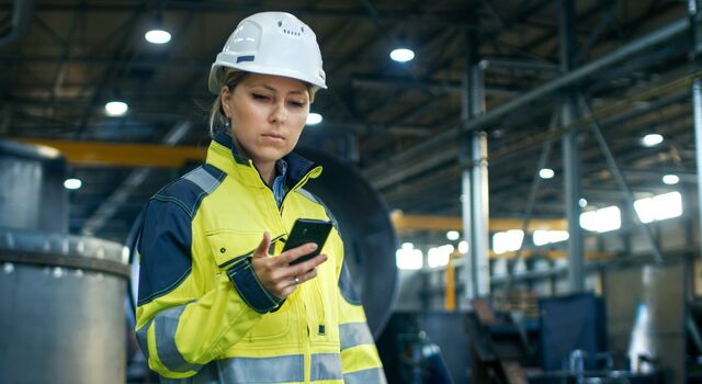COLOUR-IMAGE_female-worker-in-hi-vis-looking-at-mobile-phone_jul26