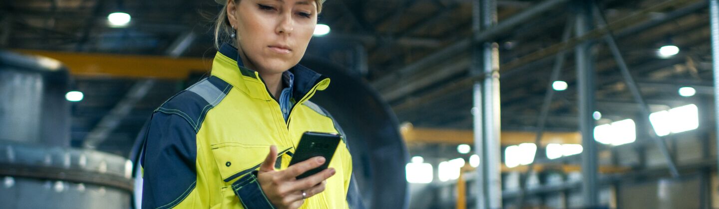 COLOUR-IMAGE_female-worker-in-hi-vis-looking-at-mobile-phone_jul26