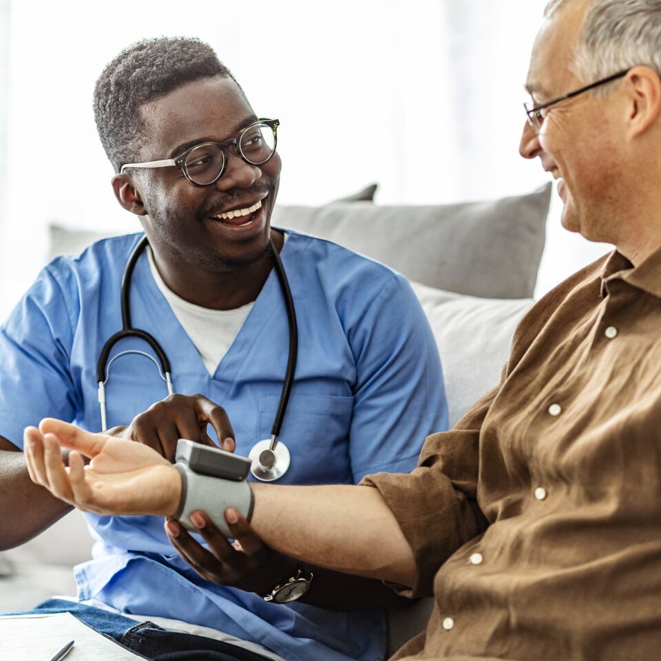 COLOUR-IMAGE_black-male-nurse-taking-pulse-of-patient-smiling_apr26