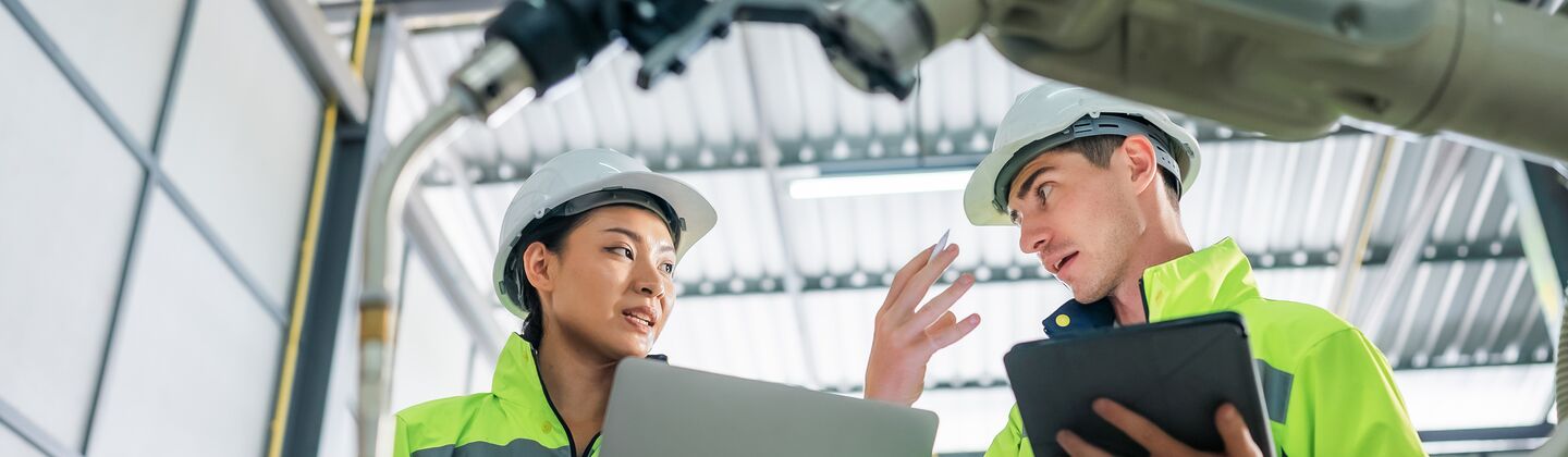 COLOUR-IMAGE_two-workers-wearing-hi-vis-coats-holding-devices_apr26