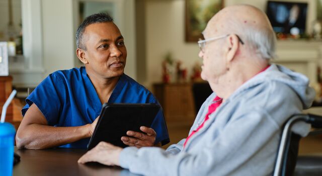 COLOUR-IMAGE_older-male-nurse-speaking-with-elderly-patient_apr26