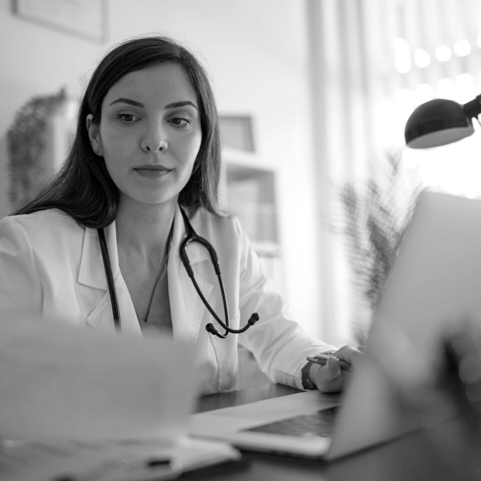 SINGLE-IMAGE_doctor-checking-paperwork-and-laptop_aug25