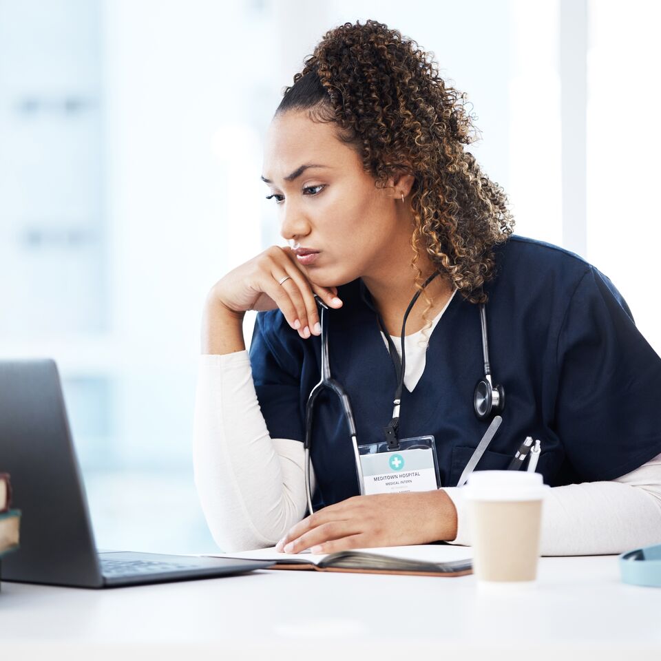 COLOUR-IMAGE_mixed-race-nurse-staring-intently-at-laptop-screen_apr26