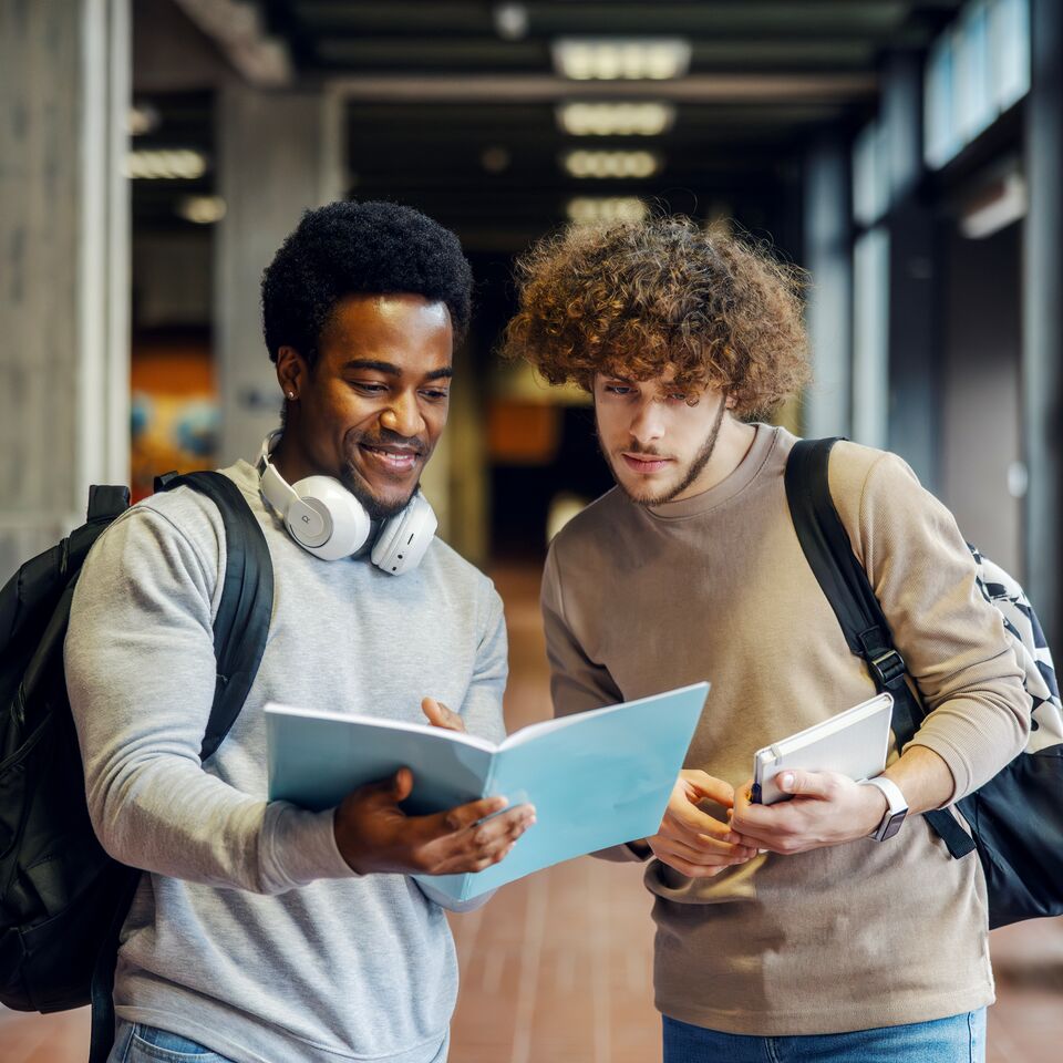 COLOUR-IMAGE_two-male-students-in-hallway-looking-at-work_apr26