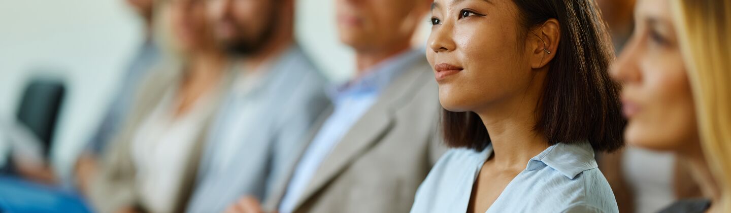 COLOUR-IMAGE_woman-in-conference-audience-smiling-and-engaged_jul26