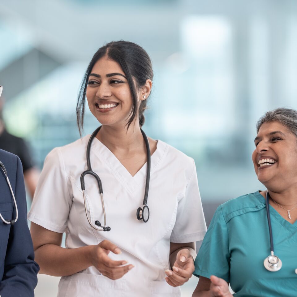 COLOUR-IMAGE_three-healthcare-professionals-laughing-in-hallway_apr26