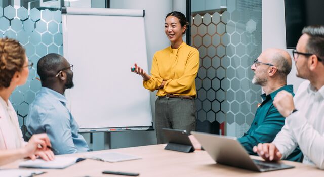 COLOUR-IMAGE_woman-in-yellow-blouse-presenting-in-team-meeting_jul26