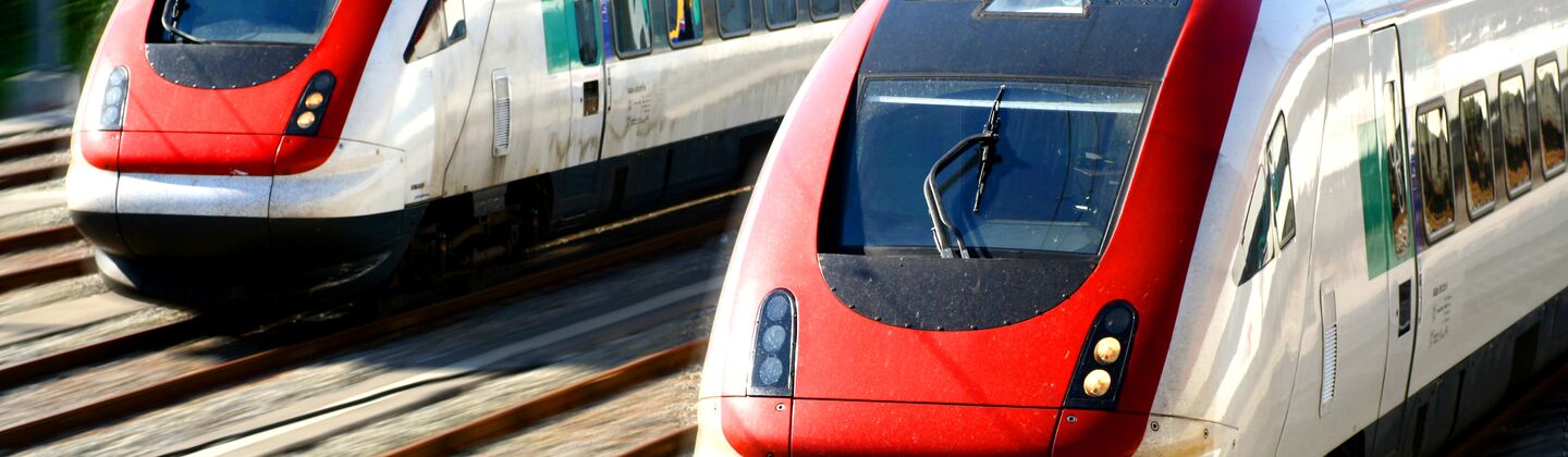 COLOUR-IMAGE_two-red-and-grey-trains-travelling-on-tracks_feb26