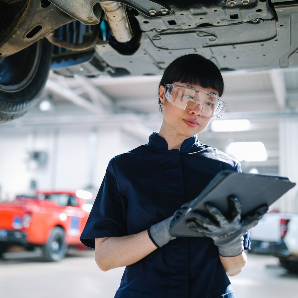 COLOUR-IMAGE_automotive-female-engineer-looking-at-tablet-in-large-industrial-mechanic-workshop_sep26
