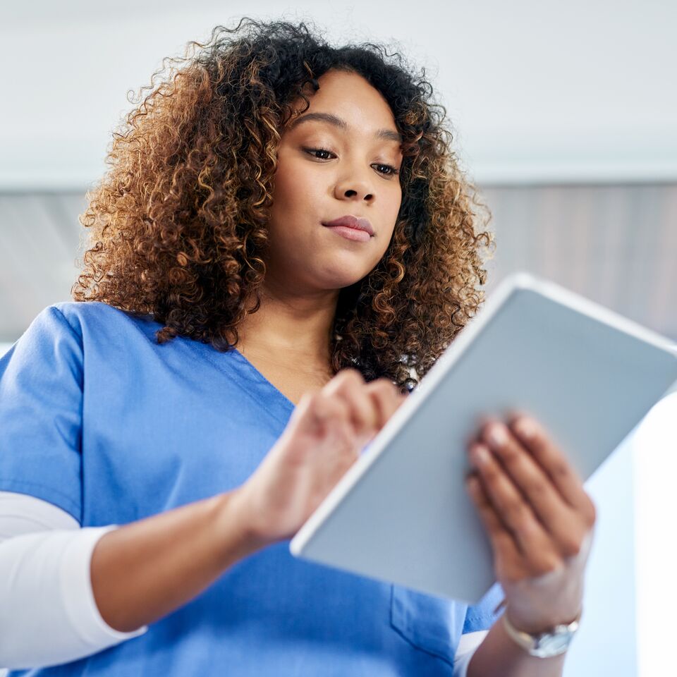 COLOUR-IMAGE_female-nurse-with-brown-curls-using-tablet_apr26