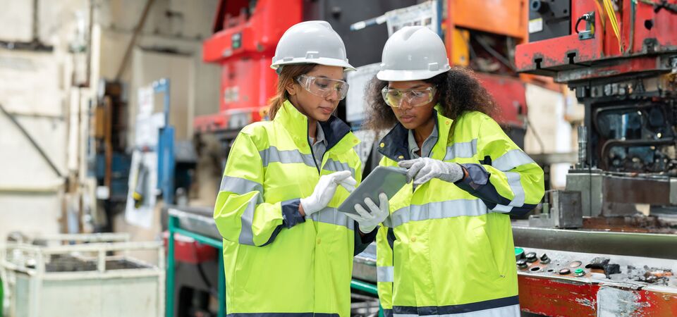COLOUR-IMAGE_two-ladies-in-hi-vis-and-hard-hats-discussing-outside-of-factory_apr26