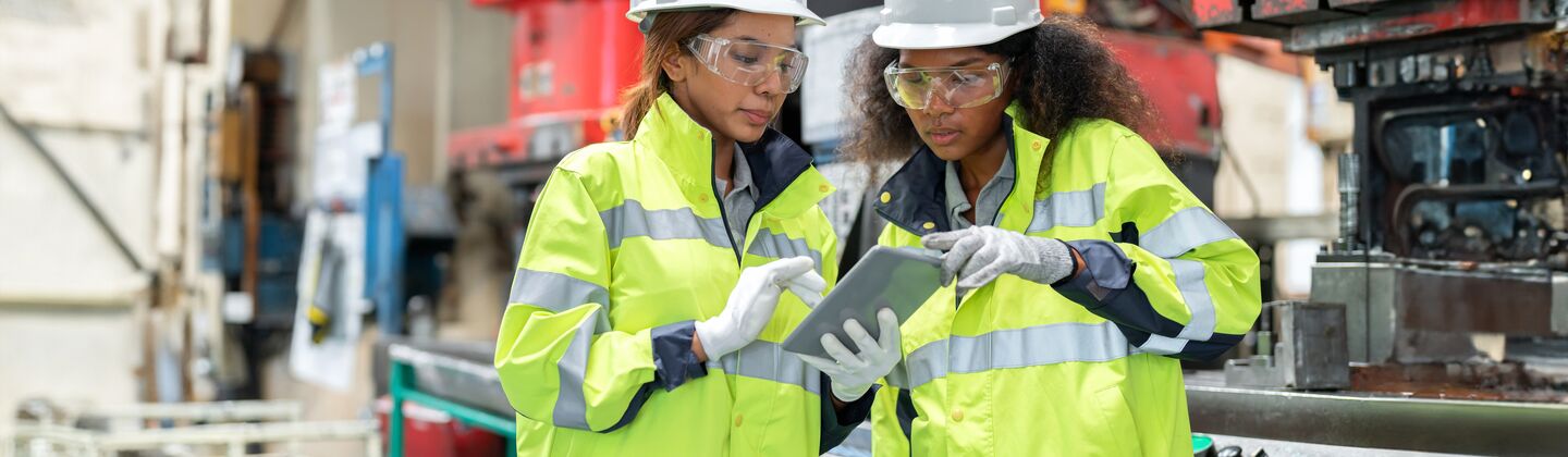 COLOUR-IMAGE_two-ladies-in-hi-vis-and-hard-hats-discussing-outside-of-factory_apr26