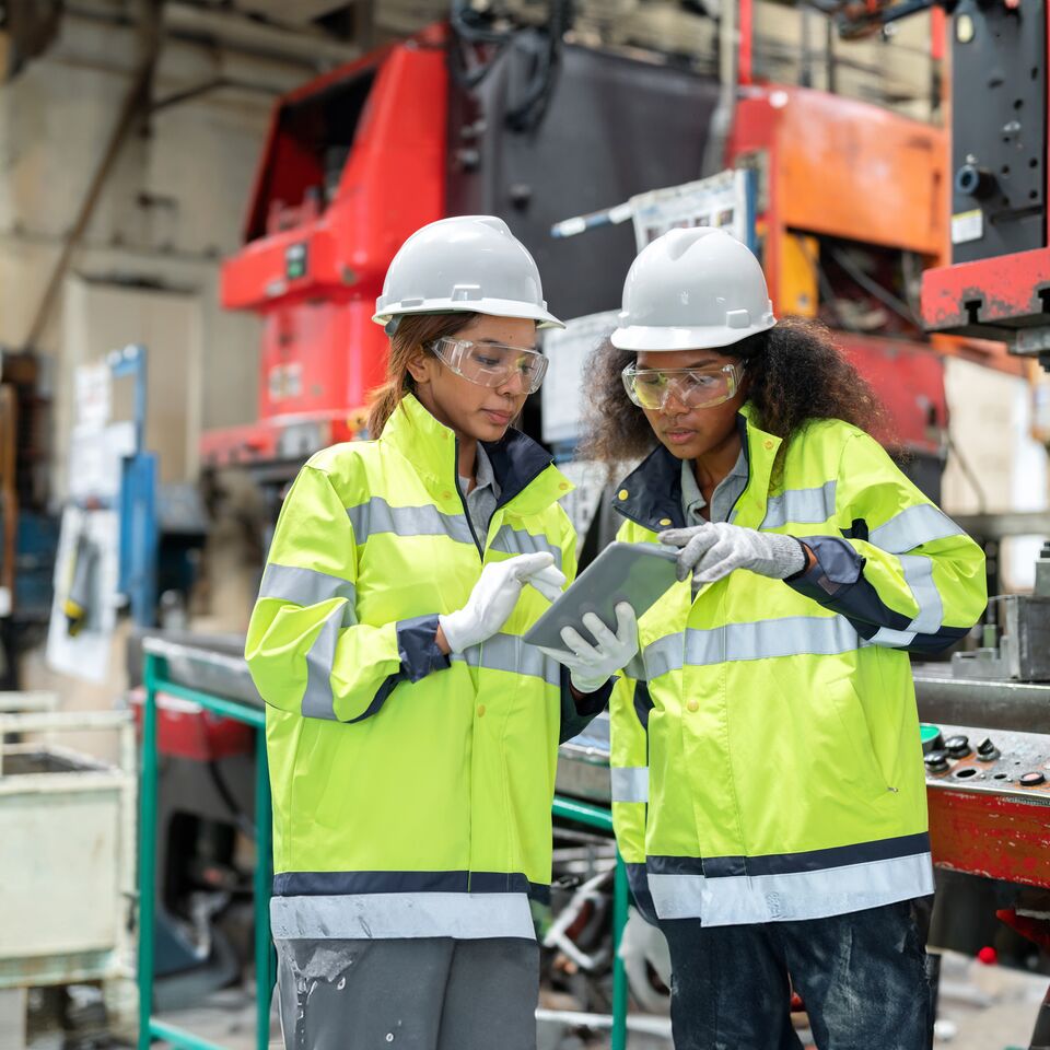 COLOUR-IMAGE_two-ladies-in-hi-vis-and-hard-hats-discussing-outside-of-factory_apr26