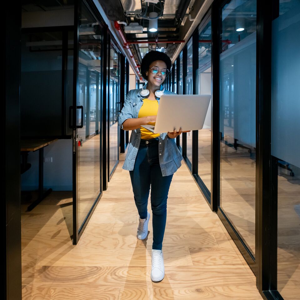 COLOUR-IMAGE_woman-laptop-device-walking-corridor-office_mar26