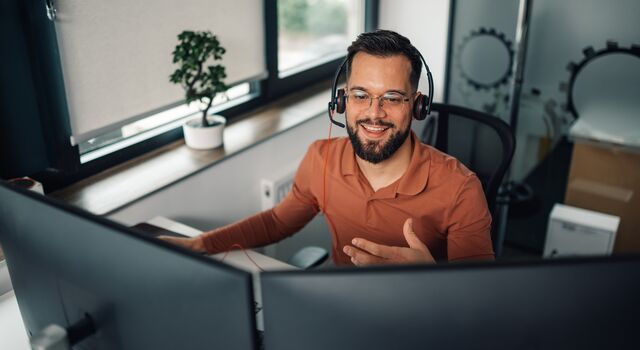 COLOUR-IMAGE_man-with-headset-working-on-dual-screens_jul26