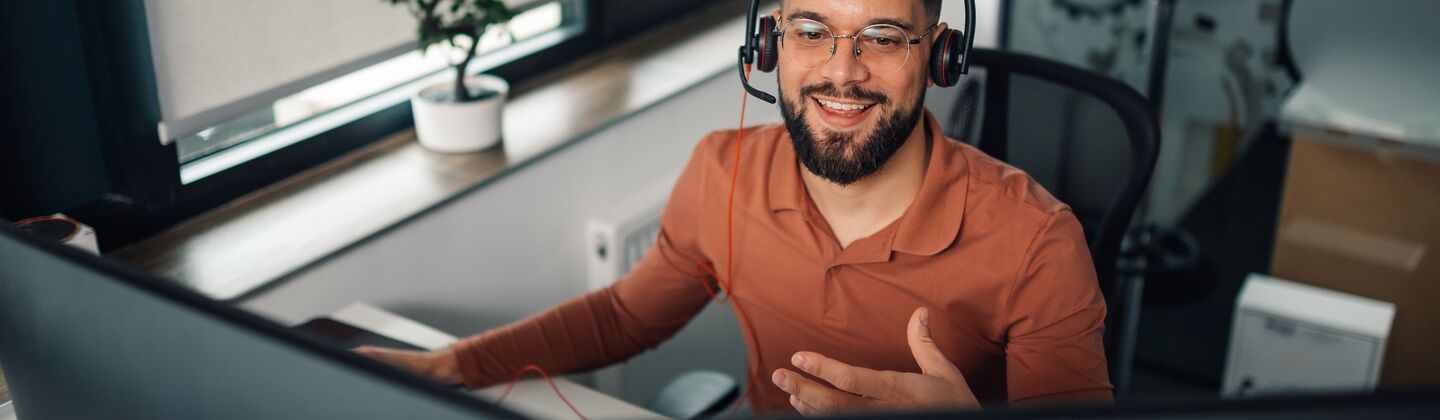 COLOUR-IMAGE_man-with-headset-working-on-dual-screens_jul26