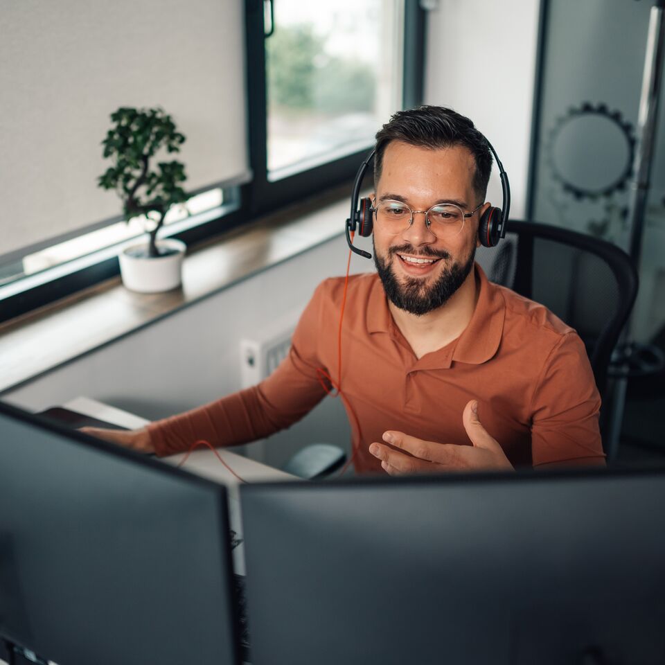 COLOUR-IMAGE_man-with-headset-working-on-dual-screens_jul26