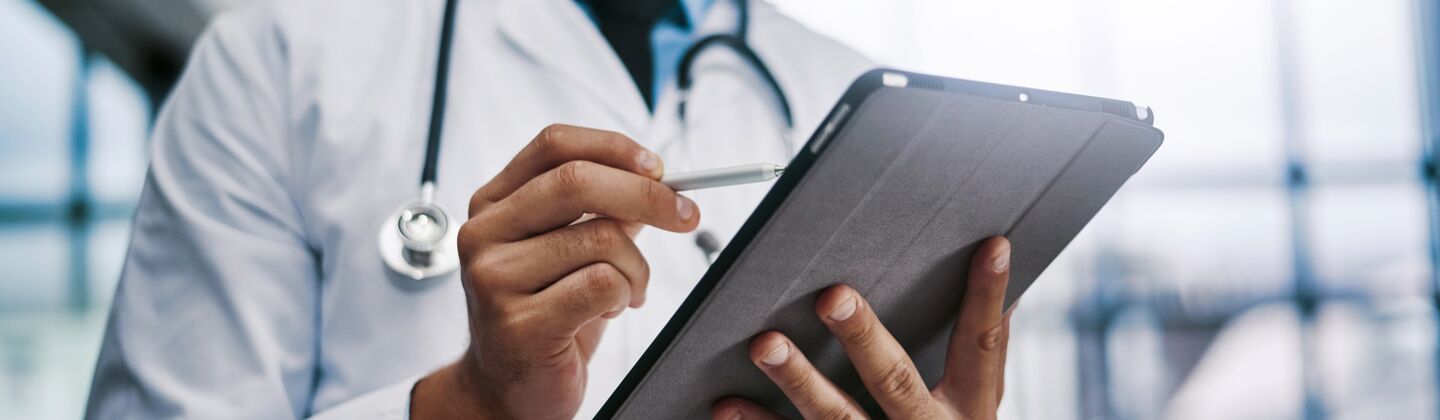 COLOUR-IMAGE_male-doctor-smiling-at-tablet-screen_apr26