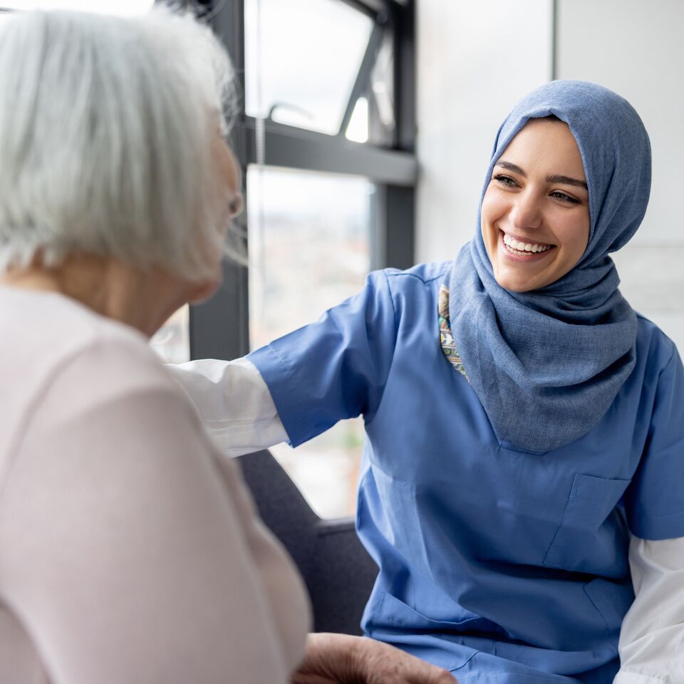 COLOUR-IMAGE_female-nurse-withblue-hijab-smiling-at-elderly-patient_apr26