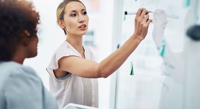 COLOUR-IMAGE_woman-writing-on-white-board_jul26