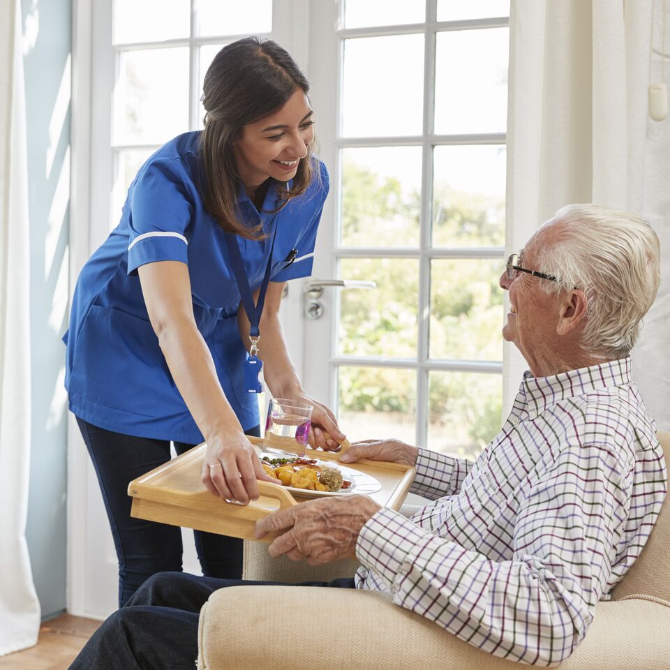 COLOUR-IMAGE_brunette-nurse-smiling-and-caring-for-elderly-patient_apr26