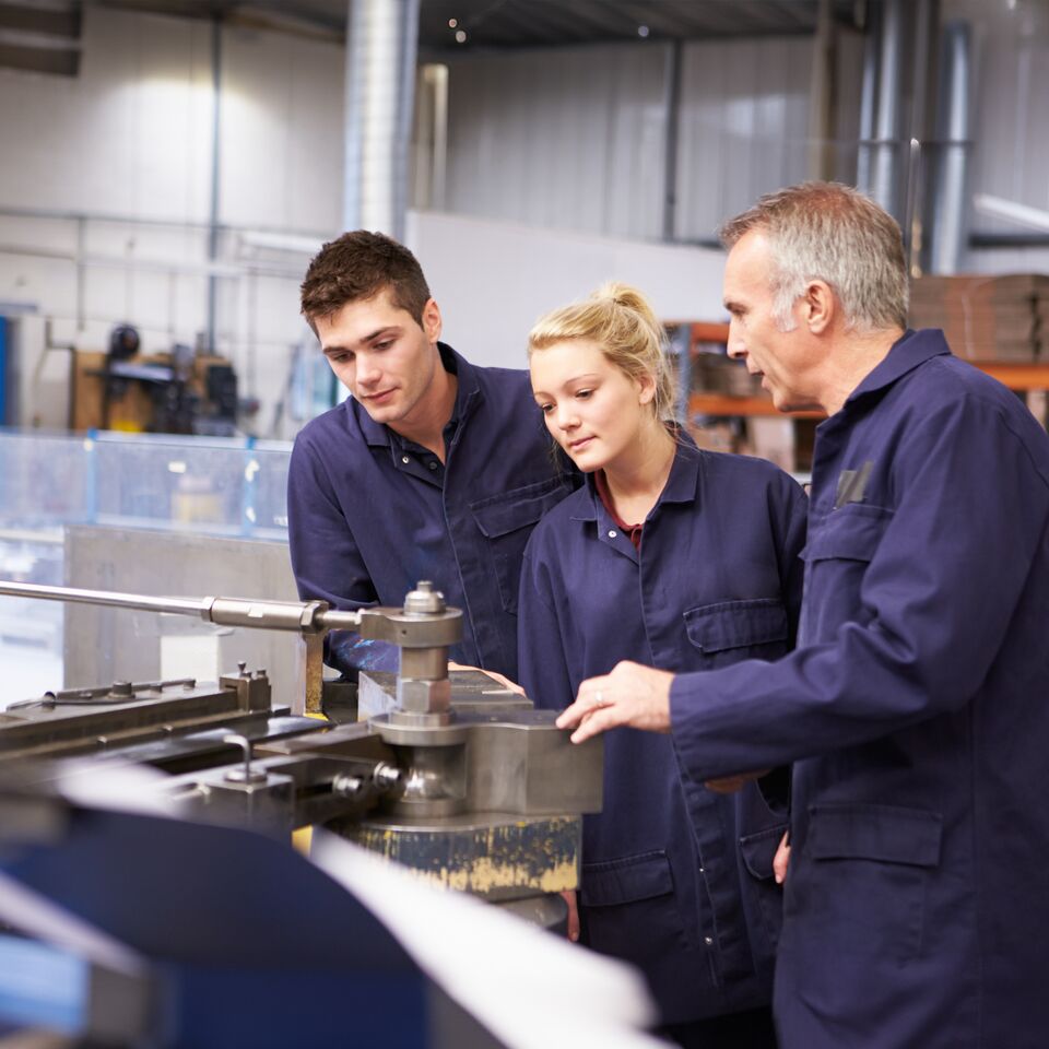 COLOUR-IMAGE_three-employees-in-factory-wearing-blue-jumpsuits_apr26