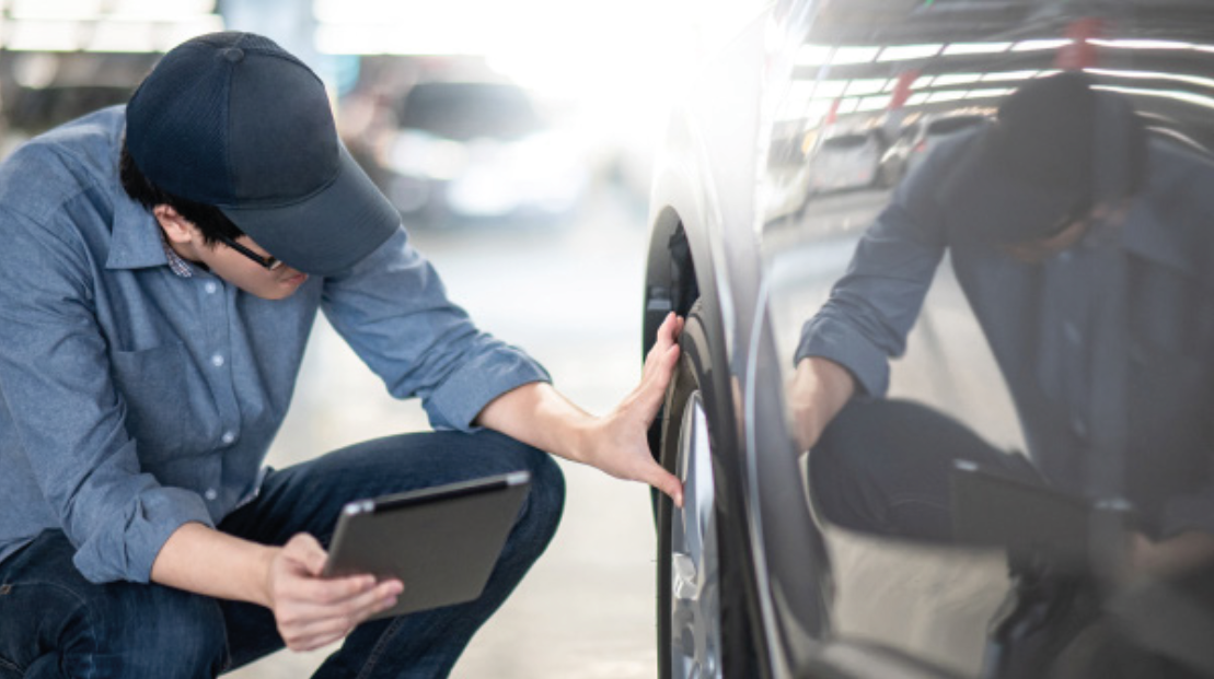 man with clipboard checking tyre